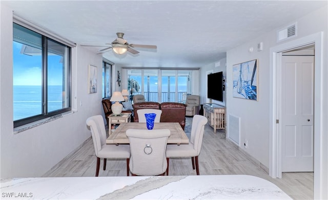 dining space with a healthy amount of sunlight, a water view, and light wood-type flooring