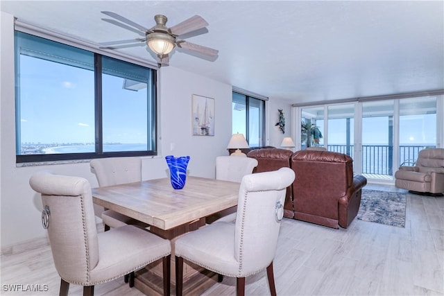 dining room featuring ceiling fan, a healthy amount of sunlight, and a wall of windows