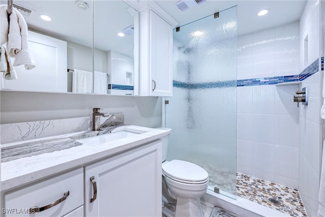 bathroom featuring a tile shower, vanity, and toilet