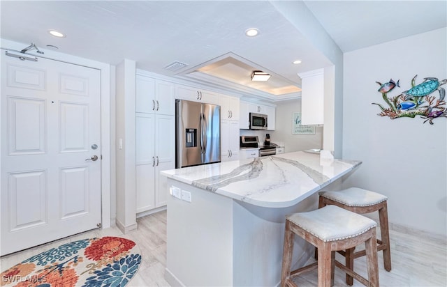 kitchen with a breakfast bar area, kitchen peninsula, white cabinetry, and appliances with stainless steel finishes