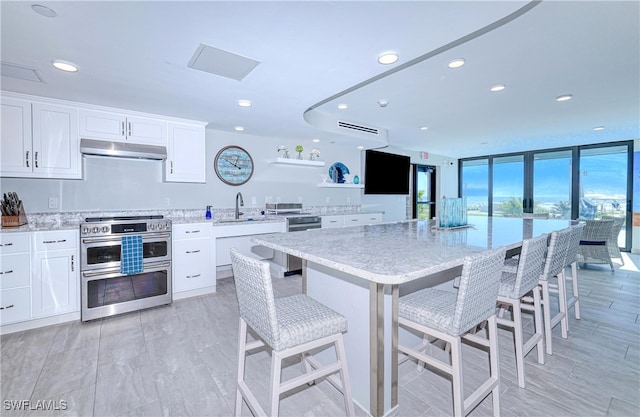 kitchen with a center island, stainless steel appliances, light stone counters, a kitchen bar, and white cabinets