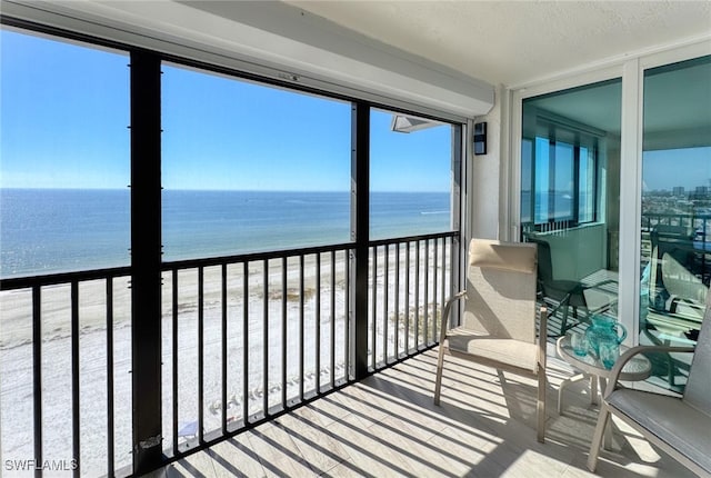 sunroom / solarium featuring a water view and a view of the beach