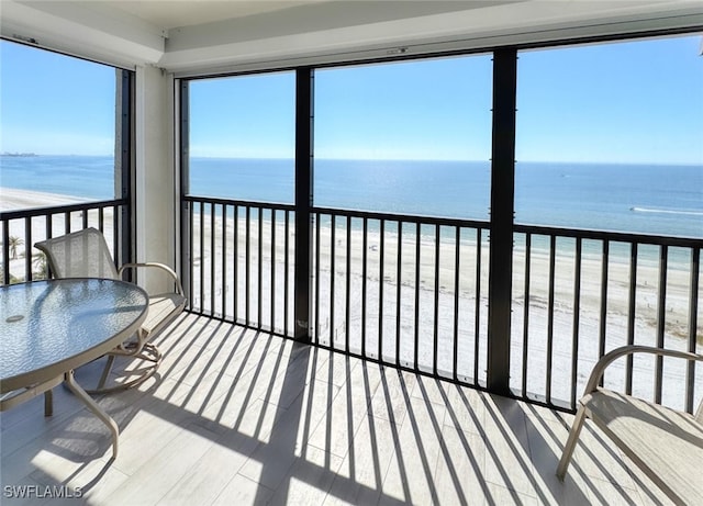 unfurnished sunroom featuring a water view and a beach view