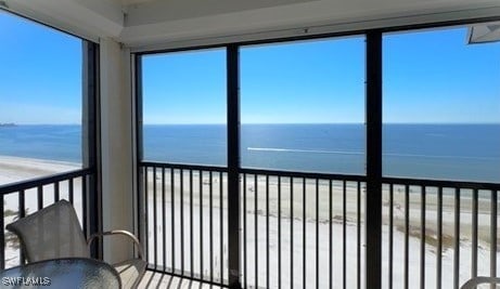 unfurnished sunroom featuring a beach view and a water view