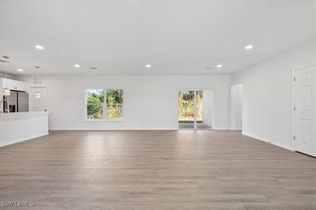 unfurnished living room featuring a healthy amount of sunlight and light hardwood / wood-style floors