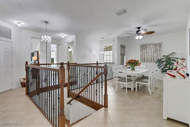 interior space with tile patterned flooring and ceiling fan with notable chandelier