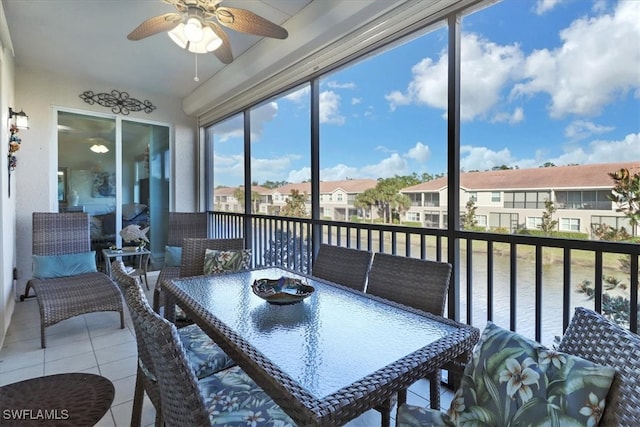 sunroom with ceiling fan and a water view