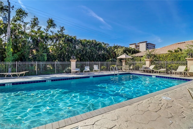 community pool with a patio area and fence