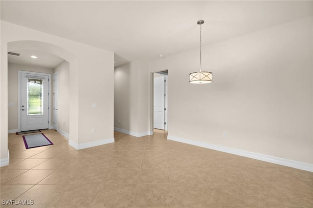 interior space featuring arched walkways, baseboards, and light tile patterned floors