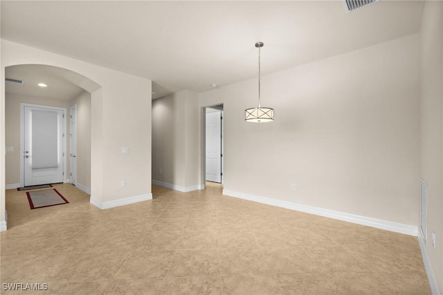 unfurnished room featuring arched walkways, visible vents, and baseboards