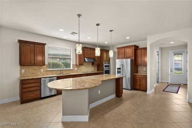 kitchen featuring a center island, arched walkways, appliances with stainless steel finishes, a sink, and under cabinet range hood