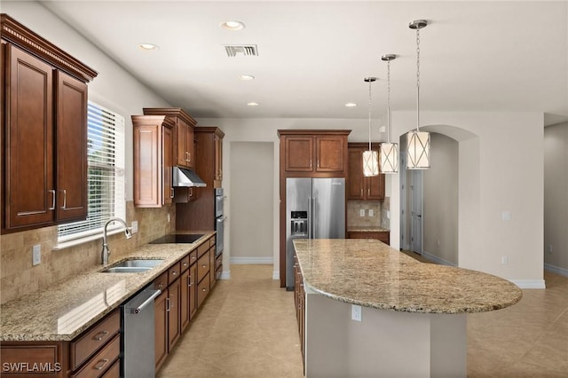 kitchen with visible vents, a kitchen island, appliances with stainless steel finishes, under cabinet range hood, and a sink