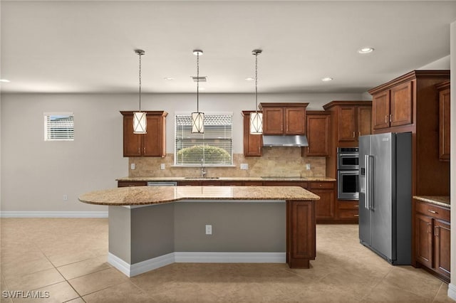 kitchen featuring appliances with stainless steel finishes, a center island, a healthy amount of sunlight, under cabinet range hood, and a sink