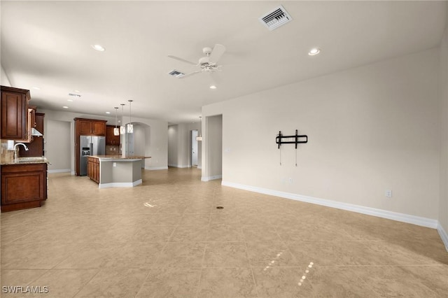 unfurnished living room with baseboards, visible vents, ceiling fan, a sink, and recessed lighting