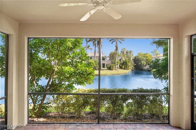 unfurnished sunroom featuring a water view and a ceiling fan