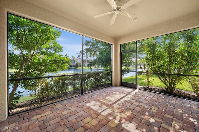 unfurnished sunroom with a ceiling fan and a water view