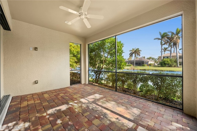 unfurnished sunroom featuring ceiling fan and a water view