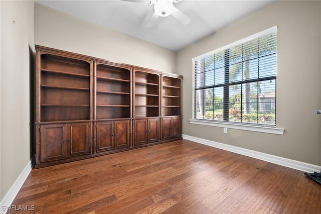 unfurnished room with ceiling fan, wood finished floors, and baseboards