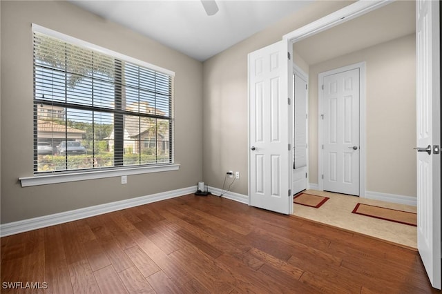 unfurnished room with a ceiling fan, baseboards, and wood finished floors