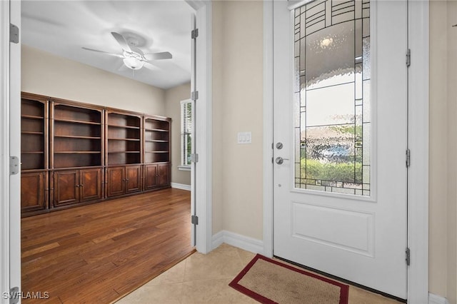 entryway with wood finished floors, a ceiling fan, and baseboards