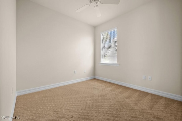 carpeted empty room with a ceiling fan and baseboards