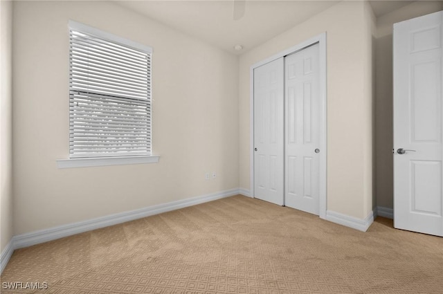 unfurnished bedroom with carpet floors, a ceiling fan, baseboards, and a closet