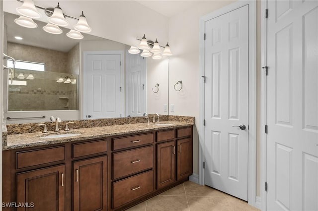 bathroom featuring double vanity, a sink, a tile shower, and tile patterned floors