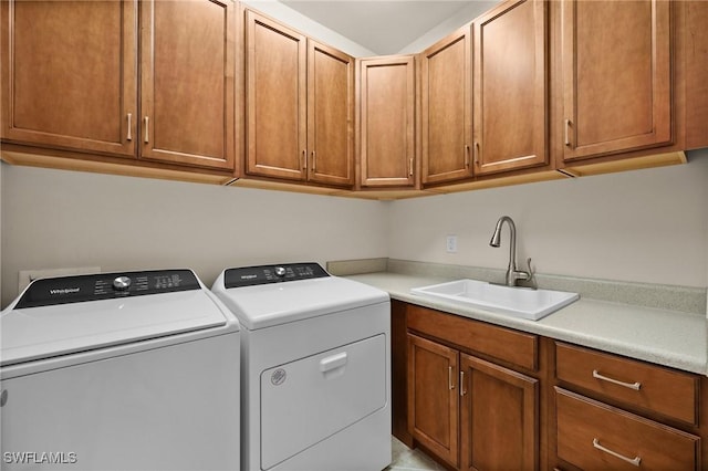 washroom with cabinet space, a sink, and washing machine and clothes dryer