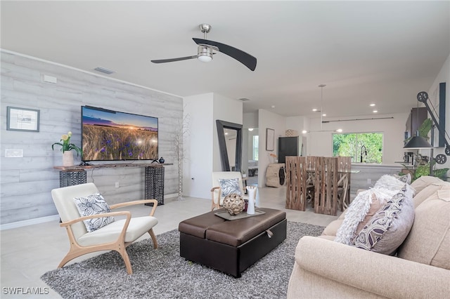 living room featuring ceiling fan, wood walls, and sink