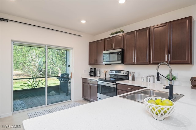 kitchen with light tile patterned flooring, appliances with stainless steel finishes, dark brown cabinetry, and sink