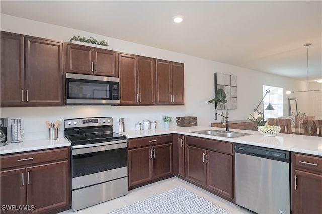 kitchen featuring pendant lighting, sink, light tile patterned floors, appliances with stainless steel finishes, and kitchen peninsula