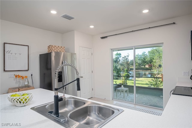 kitchen featuring stainless steel fridge, black stove, and sink