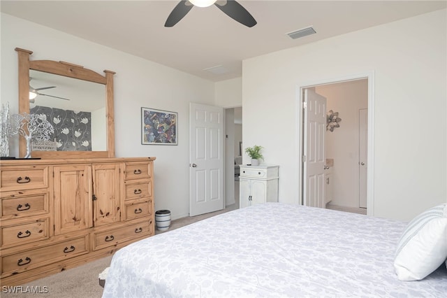 bedroom featuring light carpet, ensuite bath, and ceiling fan