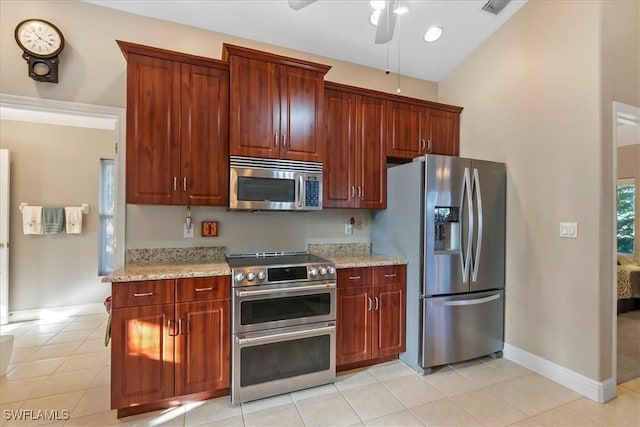 kitchen featuring ceiling fan, light stone counters, light tile patterned floors, and stainless steel appliances