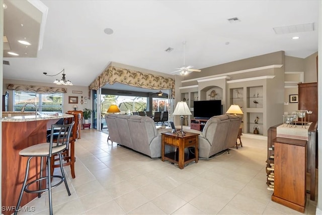 living room featuring plenty of natural light, vaulted ceiling, ceiling fan with notable chandelier, and built in shelves