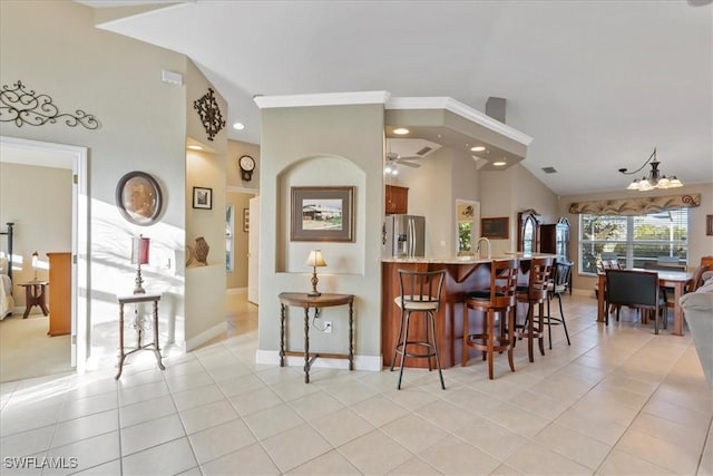 kitchen with light stone counters, stainless steel refrigerator with ice dispenser, kitchen peninsula, a breakfast bar, and light tile patterned floors