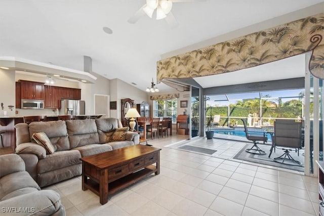 tiled living room with vaulted ceiling, ceiling fan, and a healthy amount of sunlight