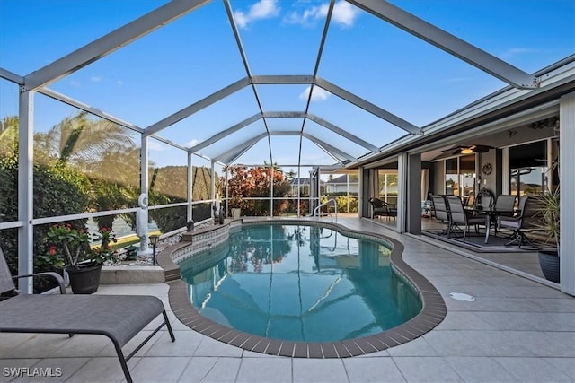 view of swimming pool with a patio, glass enclosure, and ceiling fan