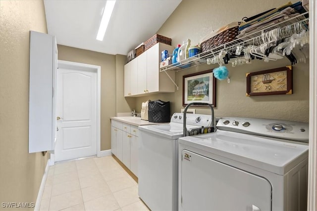 clothes washing area with cabinets, light tile patterned floors, sink, and washing machine and clothes dryer