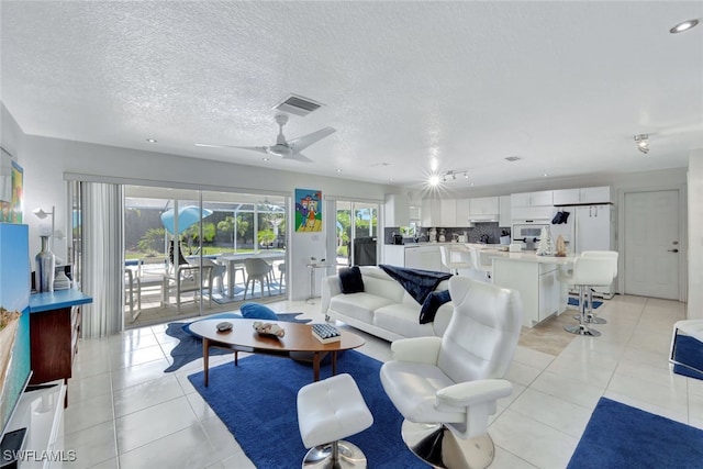 living room featuring ceiling fan, light tile patterned flooring, and a textured ceiling