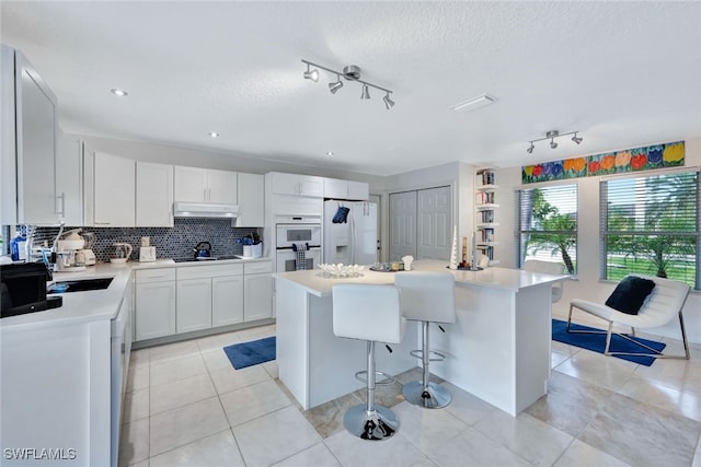 kitchen with white cabinets, a breakfast bar, a kitchen island, and white appliances