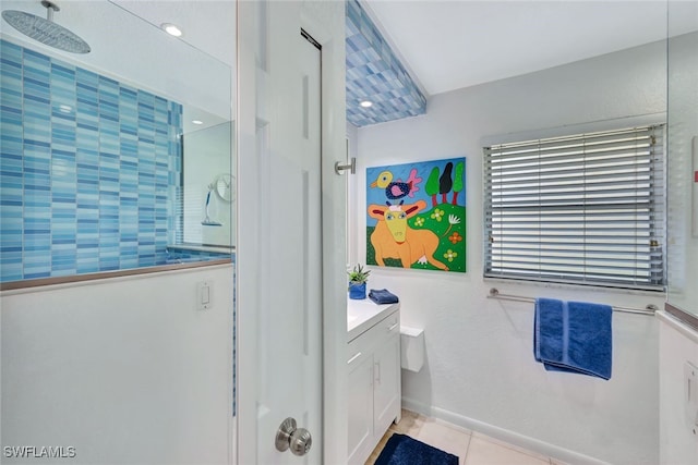 bathroom with tiled shower, vanity, and tile patterned flooring