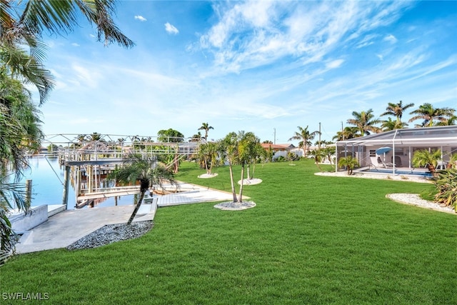 view of yard featuring glass enclosure, a water view, and a boat dock