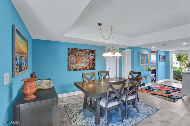 dining room with hardwood / wood-style floors, a textured ceiling, and a notable chandelier