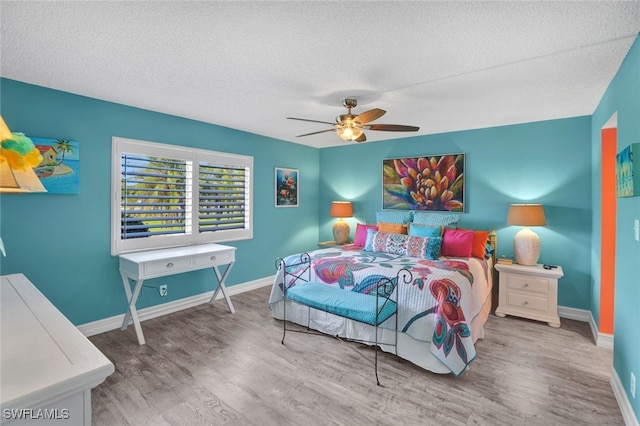 bedroom with a textured ceiling, hardwood / wood-style flooring, and ceiling fan