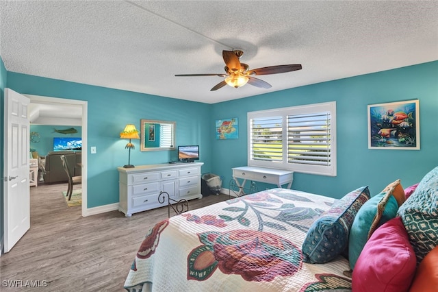 bedroom with ceiling fan, light hardwood / wood-style flooring, and a textured ceiling