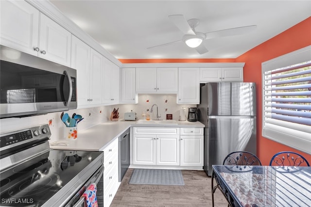 kitchen with sink, stainless steel appliances, tasteful backsplash, light hardwood / wood-style floors, and white cabinets