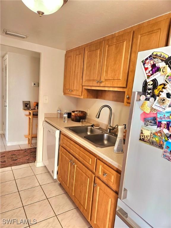 kitchen with sink, light tile patterned flooring, and white appliances