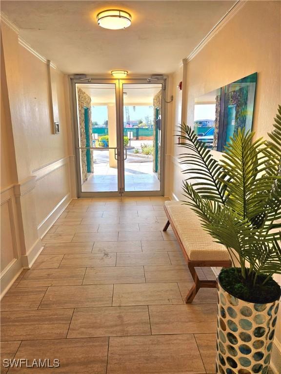 doorway featuring light hardwood / wood-style floors, crown molding, and french doors