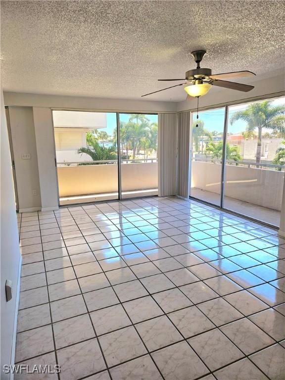 spare room with ceiling fan, light tile patterned flooring, and a textured ceiling